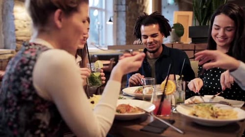 Happy friends enjoying food and drinks at a restaurant during the holidays