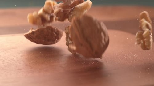 Fresh Walnuts Falling onto Wooden Cutting Board