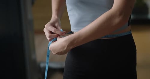 Nahaufnahme eines fitten Mädchens, das ihre perfekte Taille misst. Sportlerin, die danach zusätzliches Gewicht verliert