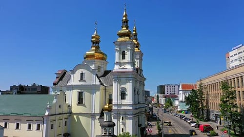 Beautiful Christian cathedral with golden cupolas shining in the bright sun. Lively city in summer.