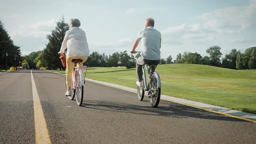Back View of Older Spouses Pedaling Vintage Bicycles Outside