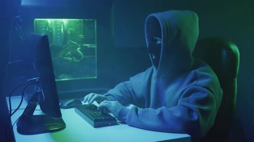 Person in Hoodie Typing at Computer at Night