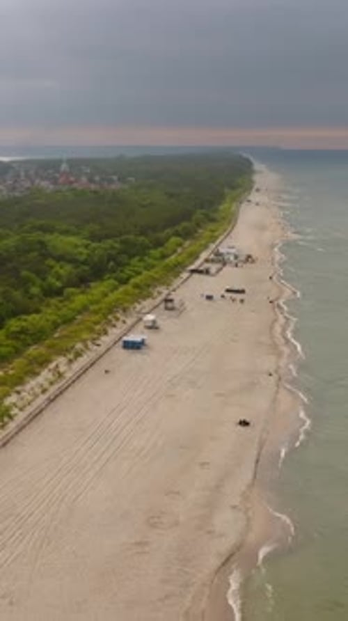 Vertical drone shot over a long beach, dramatic, summer evening in Hel, Poland