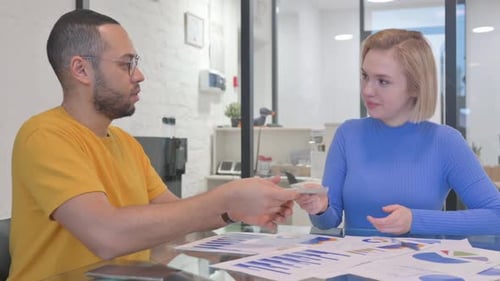 Young Woman Paying Cash to Male Teammate