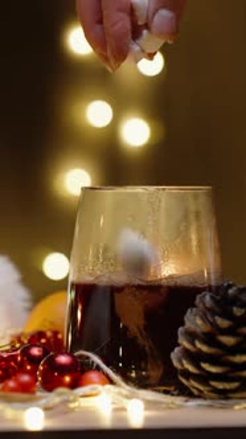 Vertical video. I throw marshmallows into hot cocoa. Christmas table with decorations and sweets.