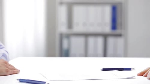 Business partners shake hands over contract at bright office table