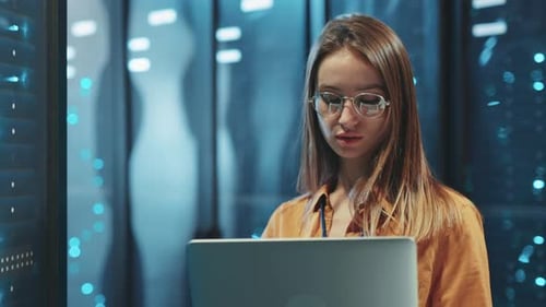 A Woman is Diligently Working in a Data Center Using a Laptop for Various Tasks and Projects