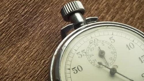 Un chronomètre blanc à cadran vintage sur fond structurel marron fait tourner la flèche