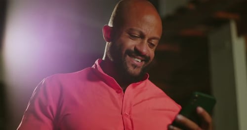 Man Smiling Looking at Phone at Night Inside