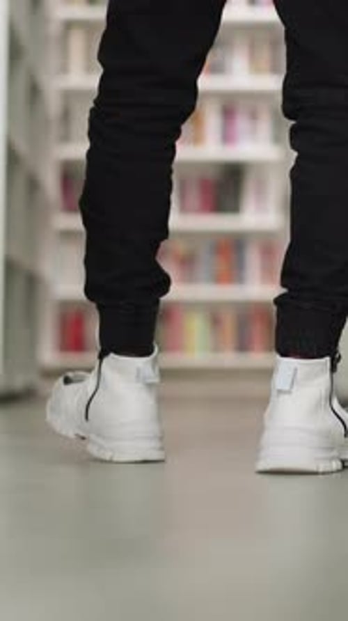 Visitor Walks Along Aisle in Library