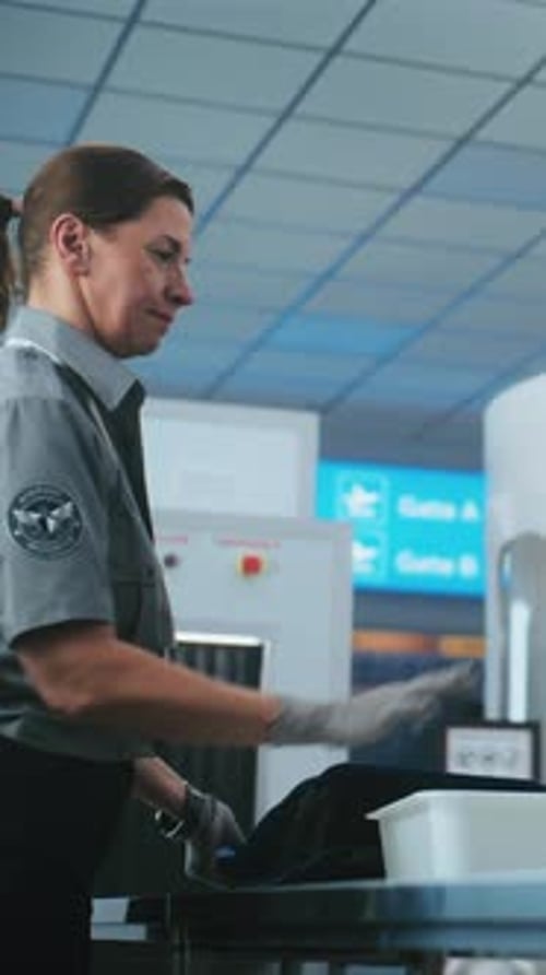 Airport Security Officer Inspecting Luggage at Checkpoint
