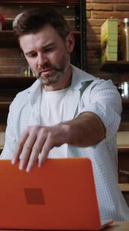 Man Celebrates Success Using Laptop Computer in Kitchen