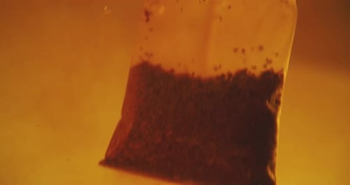 Close up of tea bag diffusing in a clear glass. Macro slow motion shot of the process of brewing