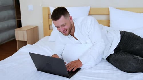 Man Using Laptop While Relaxing on Bed