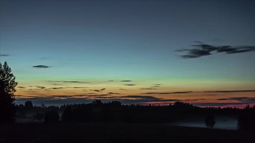Tranquil Dusk Sunset Time Lapse Of Clouds Going By Over Silhouette Farmland With Rolling Mist On Gro