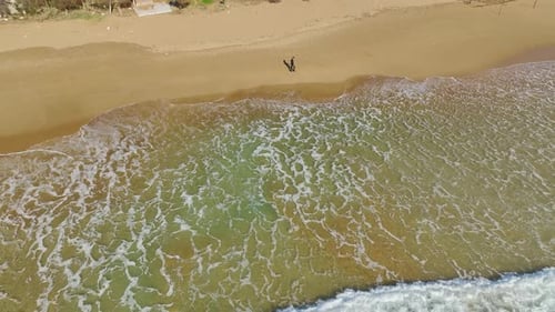 Lone Walker Luftaufnahme eines Mannes in Schwarz auf dem Sand des Mittelmeers