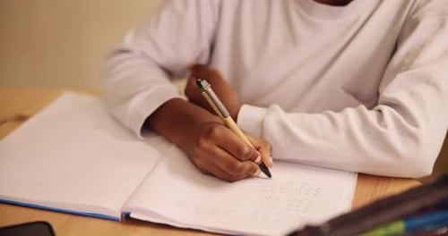 Child, hands and writing with book for mathematics, learning or education with homework at home