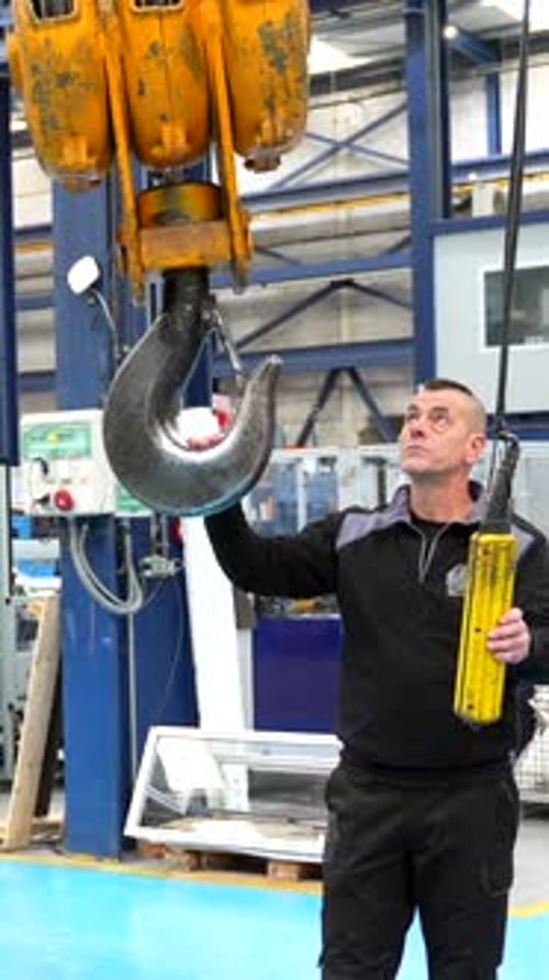 Homme contrôlant le crochet d'une grue industrielle