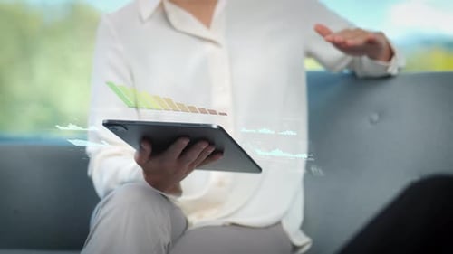 Body shot of young businesswoman with tablet screen in discussion with digital graphs financial numb