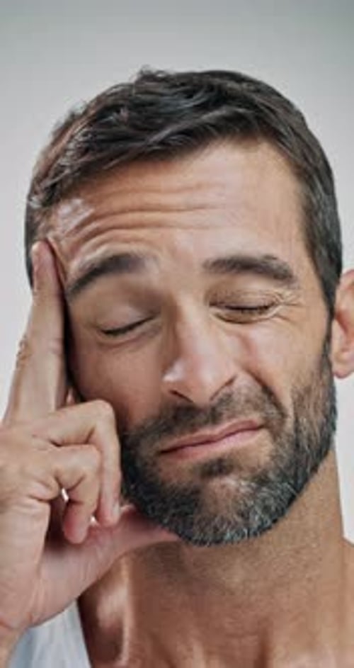 Pain, headache and face of man in studio with tension, migraine and medical crisis on white