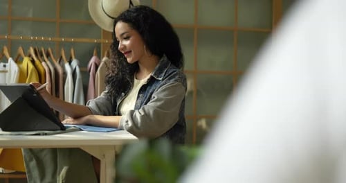 Woman Designs Fashion Using Tablet in Bright Studio
