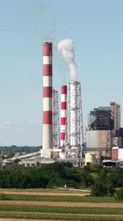 Vertical Drone Shot of Coal Electric Plant on Sunny Day, Smoke From Chimneys Under Blue Sky