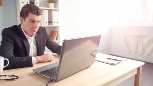 Young Man Sitting at His Desk in the Sunny Office