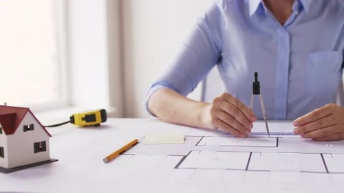 Architect designs house using blueprints and tools