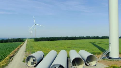 Aerial footage of the wind farm on the green field near the sea, sunny day