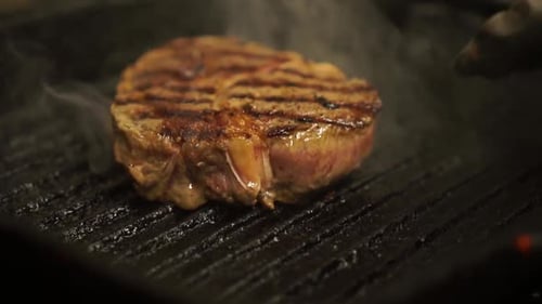 Nahaufnahme - Ein Steak auf dem Grill umdrehen