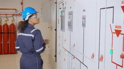 Woman Inspecting Electrical Panels in Industrial Setting