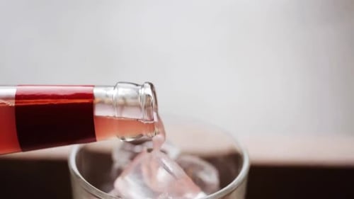 Refreshing pink soda being poured into glass with ice