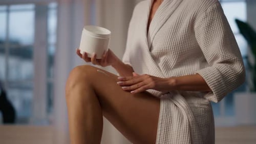 Woman applies lotion to her leg