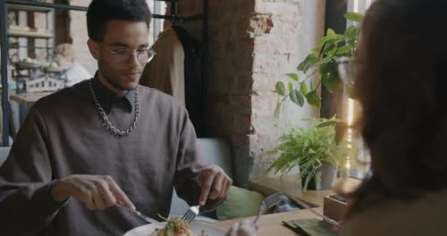 Portrait of African American Man Eating Delicious Meal and Talking to Woman Dining in Cafe Together