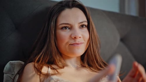 Woman Relaxes Using Smart Phone in Bed at Home