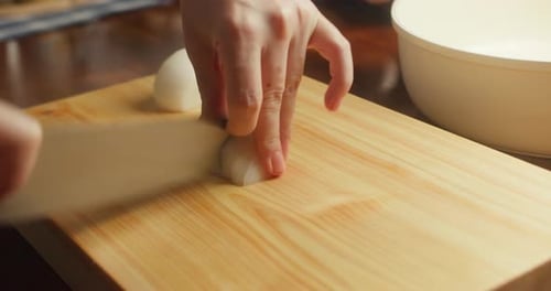 Chopping a Fresh White Onion on Wood Board