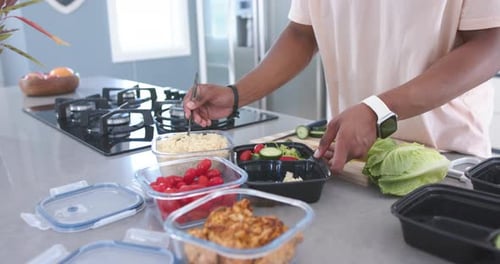 Homme afro-américain plaçant des récipients transparents, ramassant du riz dans des boîtes à repas noires au comptoir