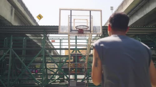Asiatischer 4K-Sportler beim Basketballschießen auf einem Tennisplatz im Freien an sonnigen Tagen.