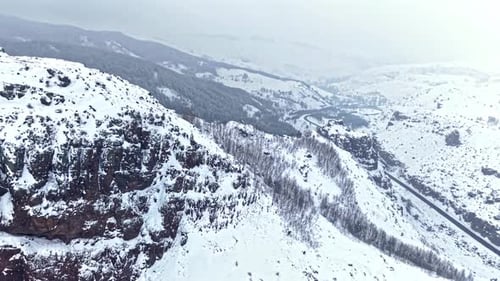 Aerial View of Snow Covered Rocky Mountains and Curved Road