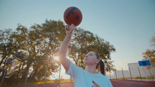 Woman Athlete Rotates Basketball Ball on Finger at Court
