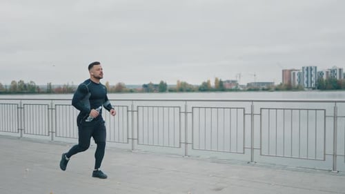 Male Jogger Running on Bridge in Earphones Athlete Doing Cardio Training Jog Exercises Morning