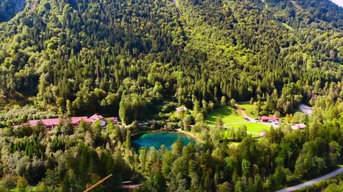 Flying closer to a little blue lake in the valley among the mountains.