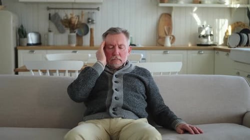 Adult Man Sitting with a Headache Indoors