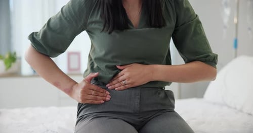 Pain, period and woman hands with stomach ache, endometriosis or PCOS health problem on a bed