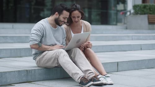 Young Couple Looking at Laptop Outdoors in City