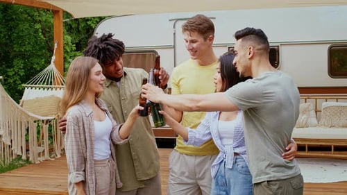 Friends Toasting Beers Together Outdoors Near Trailer
