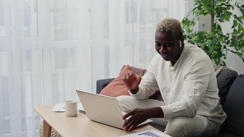 Young Adult Uses Laptop for Video Call at Home