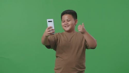 Asian Boy Make Selfie By Smartphone On Green Screen In The Studio