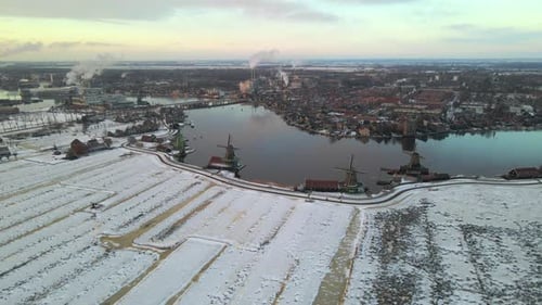 Aerial view of snowy Zaanse Schans with windmills and river, Netherlands.