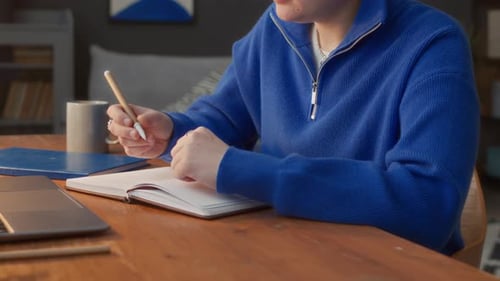 Young Adult Writing in Notebook at Home